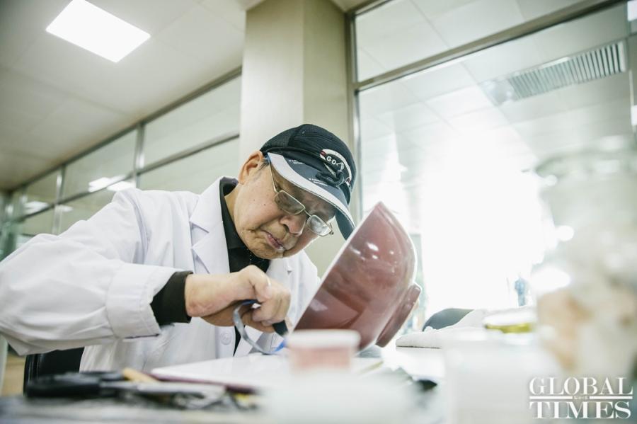 Wang Mian, Chinese ceramics repair expert, repairs a red glaze bowl used in the Qing Dynasty (1644-1911) at Yuanmingyuan Park. (Photo: Li Hao/GT)
