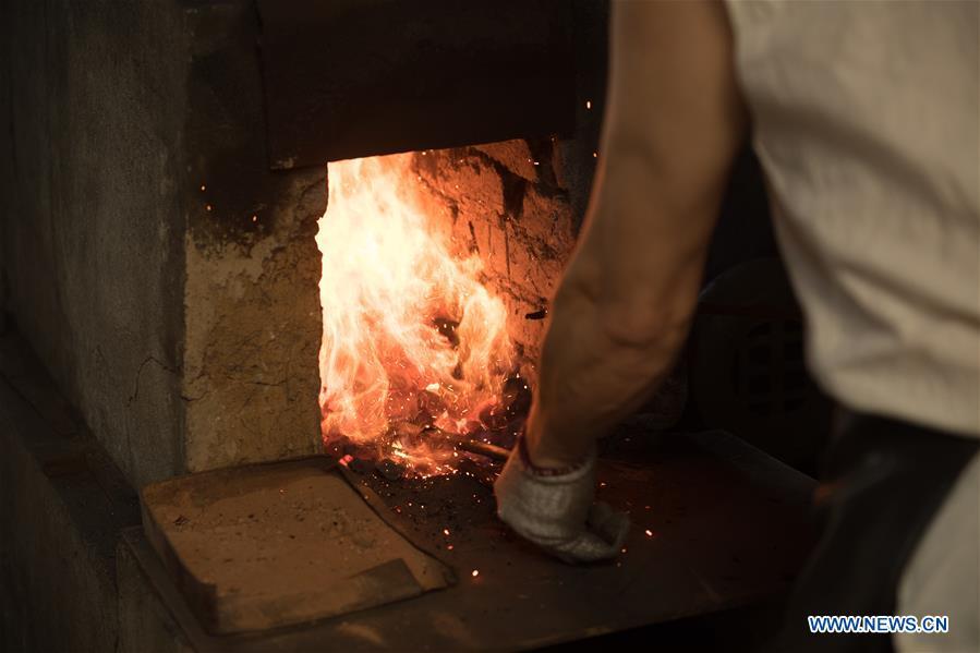 Zheng Guorong refines billet at Guyue Sword Studio in Longquan, east China\'s Zhejiang Province, May 21, 2019. For centuries, Longquan has been famed for its sword making industry. Zheng Guorong, 55, an intangible cultural heritage inheritor in Longquan Sword making, has been making sword for more than 30 years. Zheng regards sword as a symbol of spirit and devotes all to his career with awe. In his studio, the whole process of making a single sword takes two to three months, with steps including forming an idea, designing the sketch, preparing material and the final making and assembling. After setting up his studio, Zheng has trained more than 20 apprentices, who have all become sword smiths of great reputation. The old sword smith insists that Longquan sword, with a history of more than 2,500 years, deserves to be carried on in our time, both materially and spiritually. (Xinhua/Weng Xinyang)
