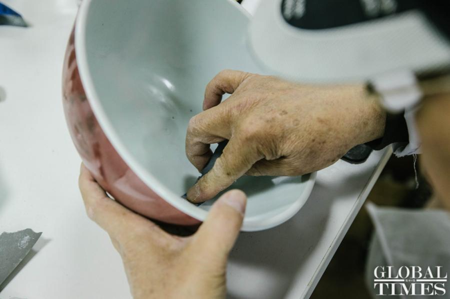 Wang Mian, a Chinese ceramics repair expert, repairs a red glaze bowl used in the Qing Dynasty (1644-1911) at Yuanmingyuan Park. (Photo: Li Hao/GT)