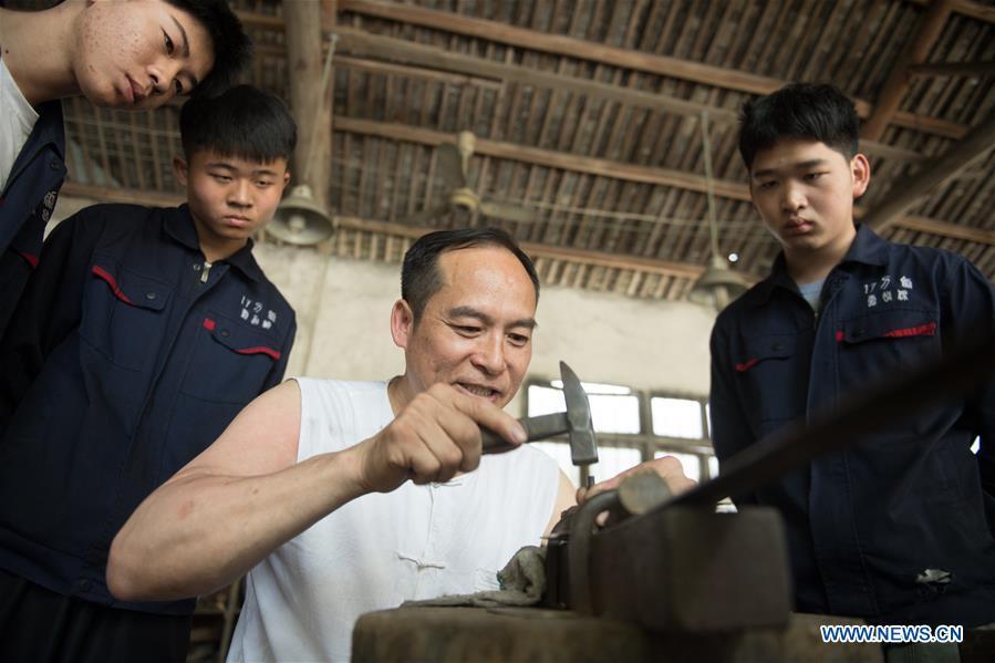 Zheng Guorong refines billet at Guyue Sword Studio in Longquan, east China\'s Zhejiang Province, May 21, 2019. For centuries, Longquan has been famed for its sword making industry. Zheng Guorong, 55, an intangible cultural heritage inheritor in Longquan Sword making, has been making sword for more than 30 years. Zheng regards sword as a symbol of spirit and devotes all to his career with awe. In his studio, the whole process of making a single sword takes two to three months, with steps including forming an idea, designing the sketch, preparing material and the final making and assembling. After setting up his studio, Zheng has trained more than 20 apprentices, who have all become sword smiths of great reputation. The old sword smith insists that Longquan sword, with a history of more than 2,500 years, deserves to be carried on in our time, both materially and spiritually. (Xinhua/Weng Xinyang)