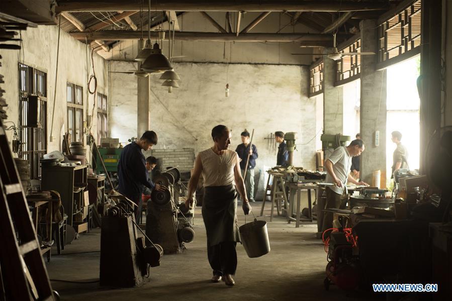 Zheng Guorong (C) and his apprentices work at Guyue Sword Studio in Longquan, east China\'s Zhejiang Province, May 21, 2019. For centuries, Longquan has been famed for its sword making industry. Zheng Guorong, 55, an intangible cultural heritage inheritor in Longquan Sword making, has been making sword for more than 30 years. Zheng regards sword as a symbol of spirit and devotes all to his career with awe. In his studio, the whole process of making a single sword takes two to three months, with steps including forming an idea, designing the sketch, preparing material and the final making and assembling. After setting up his studio, Zheng has trained more than 20 apprentices, who have all become sword smiths of great reputation. The old sword smith insists that Longquan sword, with a history of more than 2,500 years, deserves to be carried on in our time, both materially and spiritually. (Xinhua/Weng Xinyang)