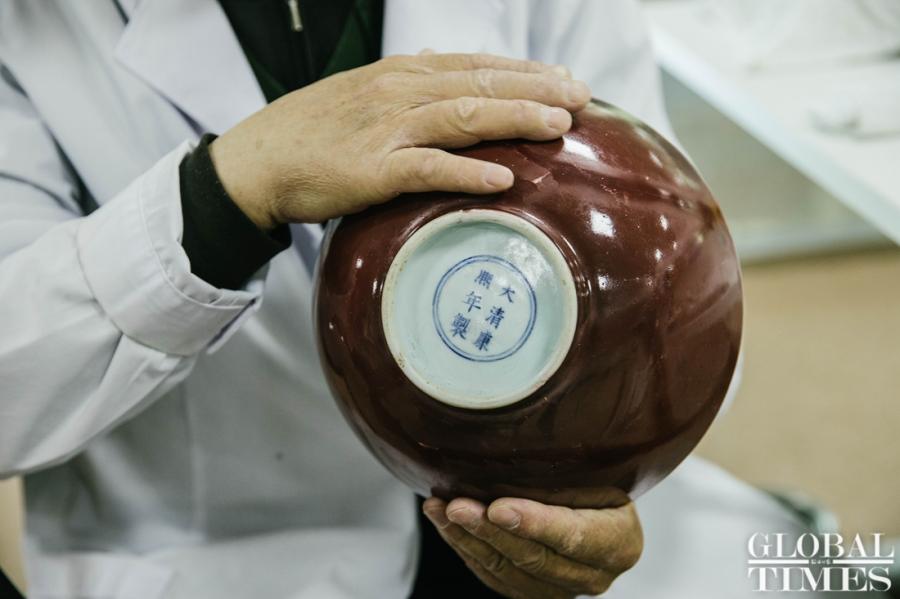 Wang Mian, a Chinese ceramics repair expert, repairs a red glaze bowl used in the Qing Dynasty (1644-1911) at Yuanmingyuan Park. (Photo: Li Hao/GT)