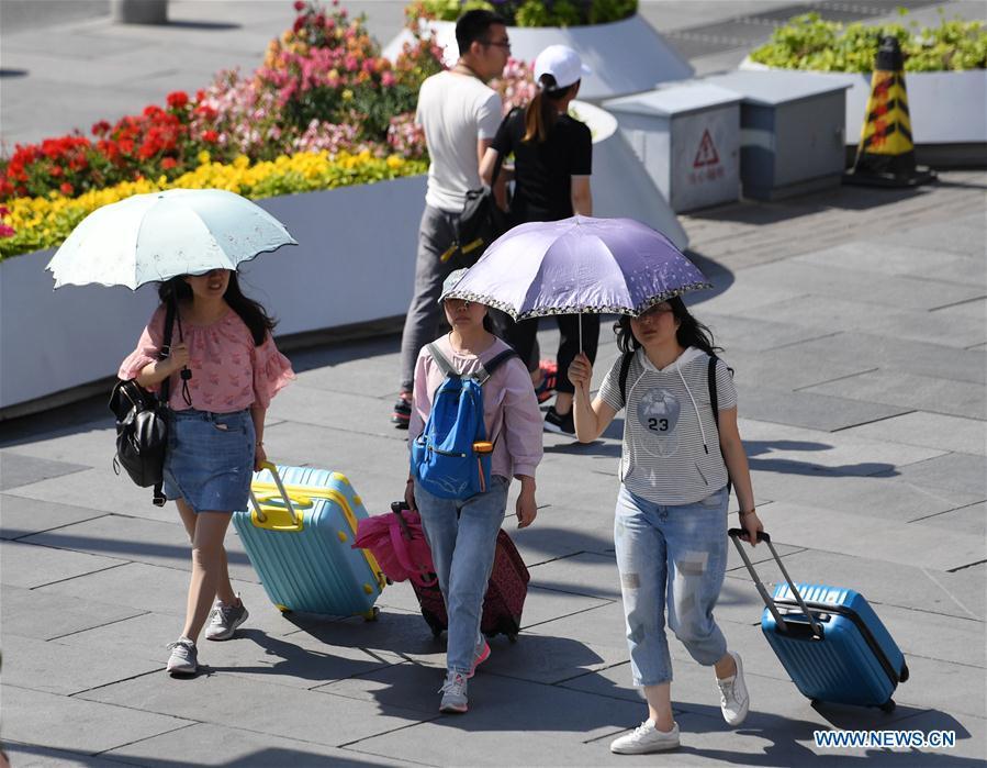 Pedestrians hold umbrellas as sun shade in Beijing, capital of China, May 22, 2019. Beijing\'s observatory issued a yellow alert on Tuesday for high temperatures over the next four days. Temperature could rise to 35 degrees Celsius from Wednesday to Saturday, and reach up to 37 degrees Celsius on Thursday. (Xinhua/Zhang Chenlin)