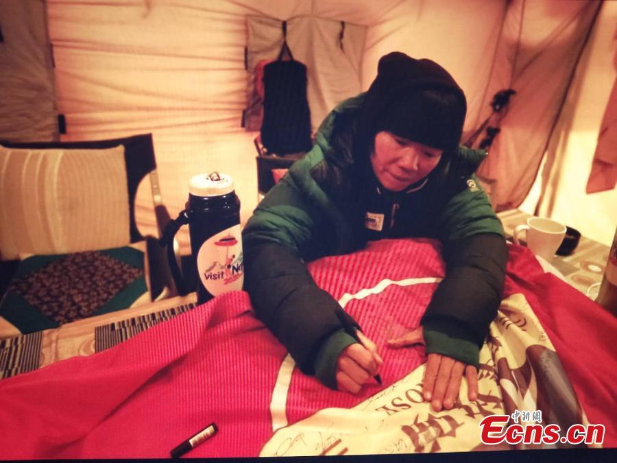 A female mountaineer signs a banner before climbing Mount Qomolangma, known as Mount Everest in the West, on May 22, 2019.(Photo/China News Service)