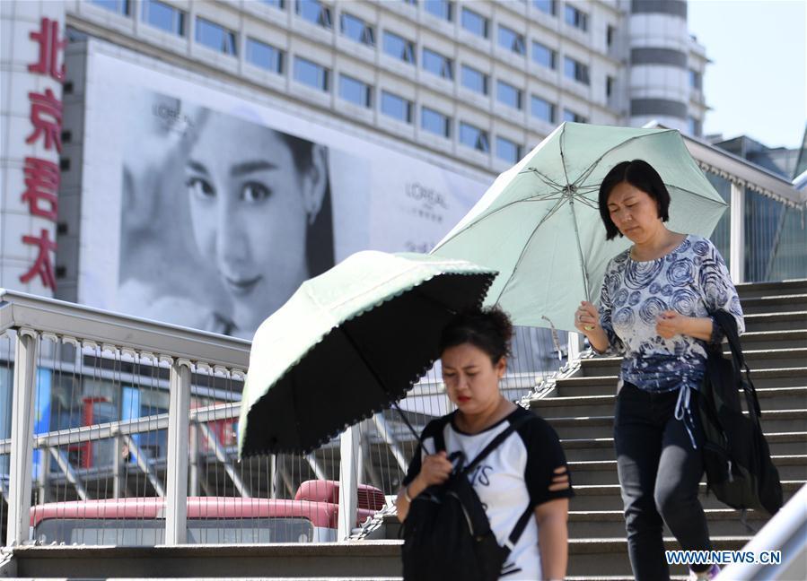 Pedestrians hold umbrellas as sun shade in Beijing, capital of China, May 22, 2019. Beijing\'s observatory issued a yellow alert on Tuesday for high temperatures over the next four days. Temperature could rise to 35 degrees Celsius from Wednesday to Saturday, and reach up to 37 degrees Celsius on Thursday. (Xinhua/Zhang Chenlin)