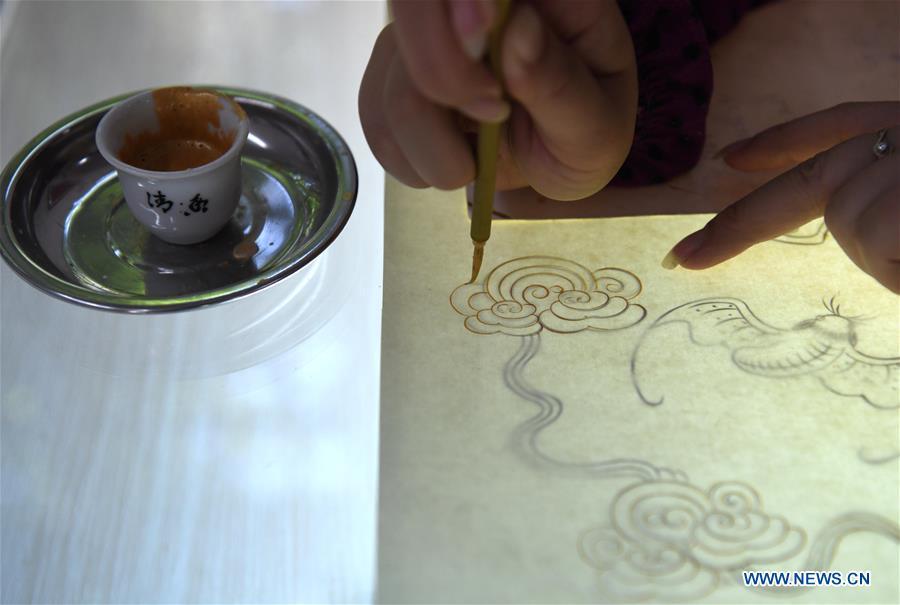 A worker applies gold paint to a piece of Fenlajian paper at a workshop run by paper artisan Liu Jing in Huanglu Township of Chaohu, east China\'s Anhui Province, May 23, 2019. Fenlajian is a high-end wax mineral paper which dates back to the Tang dynasty (618-907). For centuries, access to the Fenlajian paper had remained a privilege reserved solely for China\'s imperial families, due to the costly materials and the set of complicated procedures involved in its making. The techniques in producing this fine writing and painting material even became lost in the late Qing dynasty (1644-1911), until Liu Jing, an Anhui-based paper artisan, managed to revive them through constant trials by the end of the 20th century. Born in a family of paper-makers, Liu now runs a paper workshop dedicated to making Fenlajian and other classical papers while promoting their know-hows. Liu\'s classical paper processing techniques were listed as a national intangible cultural heritage in 2008, and he himself was named as a national representative inheritor to the aforementioned techniques in 2018. (Xinhua/Liu Junxi)