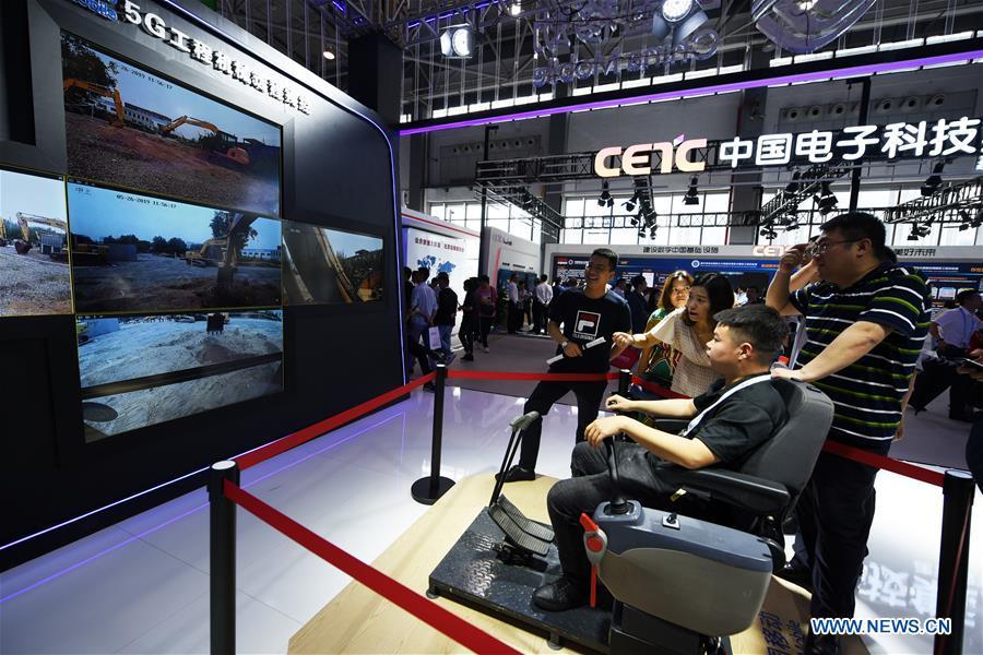 A visitor operates an excavator by a remote control system via 5G technology during China International Big Data Industry Expo 2019 in Guiyang, southwest China\'s Guizhou Province, May 26, 2019. The expo on big data opened Sunday in Guizhou Province, focusing on the latest innovation of the technology and its applications. The four-day expo will be attended by 448 enterprises from 59 countries and regions, according to the organizing committee. (Xinhua/Yang Wenbin)