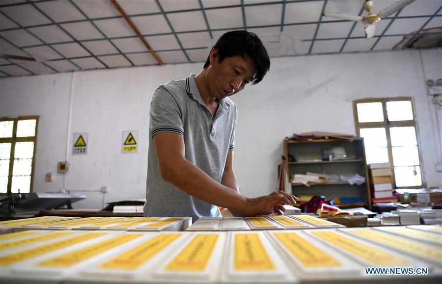 A worker wraps up Fenlajian paper products at a workshop run by paper artisan Liu Jing in Huanglu Township of Chaohu, east China\'s Anhui Province, May 23, 2019. Fenlajian is a high-end wax mineral paper which dates back to the Tang dynasty (618-907). For centuries, access to the Fenlajian paper had remained a privilege reserved solely for China\'s imperial families, due to the costly materials and the set of complicated procedures involved in its making. The techniques in producing this fine writing and painting material even became lost in the late Qing dynasty (1644-1911), until Liu Jing, an Anhui-based paper artisan, managed to revive them through constant trials by the end of the 20th century. Born in a family of paper-makers, Liu now runs a paper workshop dedicated to making Fenlajian and other classical papers while promoting their know-hows. Liu\'s classical paper processing techniques were listed as a national intangible cultural heritage in 2008, and he himself was named as a national representative inheritor to the aforementioned techniques in 2018. (Xinhua/Liu Junxi)
