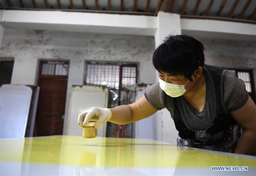 A worker scatters gold powder onto a piece of Fenlajian paper at a workshop run by paper artisan Liu Jing in Huanglu Township of Chaohu, east China\'s Anhui Province, May 23, 2019. Fenlajian is a high-end wax mineral paper which dates back to the Tang dynasty (618-907). For centuries, access to the Fenlajian paper had remained a privilege reserved solely for China\'s imperial families, due to the costly materials and the set of complicated procedures involved in its making. The techniques in producing this fine writing and painting material even became lost in the late Qing dynasty (1644-1911), until Liu Jing, an Anhui-based paper artisan, managed to revive them through constant trials by the end of the 20th century. Born in a family of paper-makers, Liu now runs a paper workshop dedicated to making Fenlajian and other classical papers while promoting their know-hows. Liu\'s classical paper processing techniques were listed as a national intangible cultural heritage in 2008, and he himself was named as a national representative inheritor to the aforementioned techniques in 2018. (Xinhua/Liu Junxi)