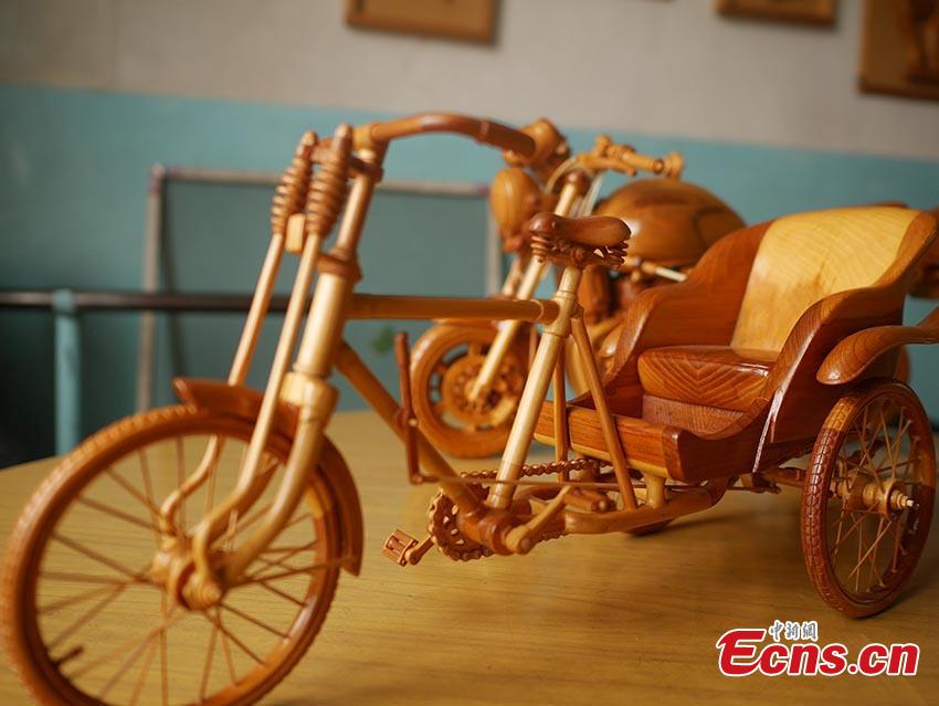 Chuai Mege shows his hand-made miniature motorcycles carved out of wood in Jilin City, Jilin Province. A former automobile mechanic, the 66-year-old man has been fascinated with making miniature motorcycles for 24 years. He said he usually needs a whole year to complete the making a miniature motorcycle because of his attention to detail and quality. For example, he needs to carve over 700 motorcycle parts including  tires, the dashboard, and even screws. (Photo: China News Service/Cang Yan)