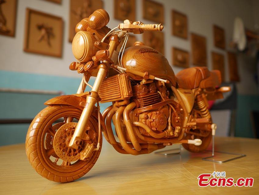 Chuai Mege shows his hand-made miniature motorcycles carved out of wood in Jilin City, Jilin Province. A former automobile mechanic, the 66-year-old man has been fascinated with making miniature motorcycles for 24 years. He said he usually needs a whole year to complete the making a miniature motorcycle because of his attention to detail and quality. For example, he needs to carve over 700 motorcycle parts including  tires, the dashboard, and even screws. (Photo: China News Service/Cang Yan)