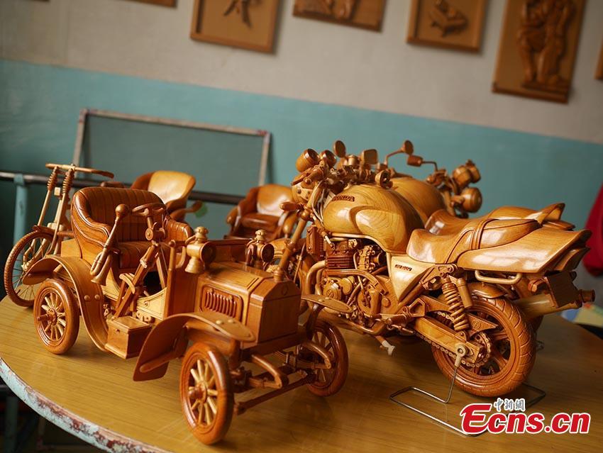 Chuai Mege shows his hand-made miniature motorcycles carved out of wood in Jilin City, Jilin Province. A former automobile mechanic, the 66-year-old man has been fascinated with making miniature motorcycles for 24 years. He said he usually needs a whole year to complete the making a miniature motorcycle because of his attention to detail and quality. For example, he needs to carve over 700 motorcycle parts including  tires, the dashboard, and even screws. (Photo: China News Service/Cang Yan)