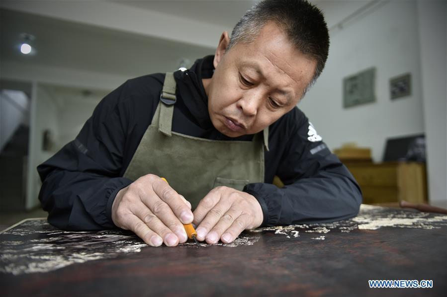 Chen Dongming works on a wood-block painting at his studio in Huanren County of Benxi, northeast China\'s Liaoning Province, May 27, 2019. Chen Dongming, a 52-year-old wood-block painter from Wafang Village of Huanren County in Benxi, learned the techniques from his grandfather since young. As an inheritor of Huanren wood-block painting, a provincial intangible cultural heritage in Liaoning, Chen has been committed to making a proper integration of traditional Chinese landscape paintings and wood-block New Year paintings to promote the craft in an innovative way. (Xinhua/Yao Jianfeng)