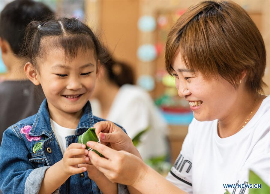A woman and a child make Zongzi, a kind of rice dumpling wrapped up with bamboo leaves, as part of the traditional folk customs to celebrate the upcoming Duanwu Festival in Zigui County of Yichang, central China\'s Hubei Province, May 29, 2019. Duanwu Festival is traditionally celebrated on the fifth day of the fifth month on Chinese lunar calendar. (Xinhua/Zheng Jiayu)