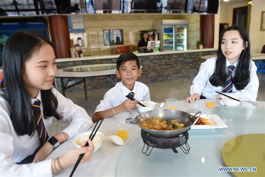 Thuch Salik (C) dines with classmates at a foreign language school in Zhuji, east China\'s Zhejiang Province, May 29, 2019. Thuch Salik became viral overnight when a video clip showing him selling souvenirs in a dozen distinct languages near Angkor Wat was shared online on November 2018. Born in a family with financial difficulties, the 14-year-old Cambodian boy got global attention for his multilingual talent. In May, Salik was offered a place at a foreign language school in Zhuji of east China\'s Zhejiang Province on an education programme funded by a private sponsor in China. Salik said he has high expectations for his education opportunity and life in China. (Xinhua/Han Chuanhao)