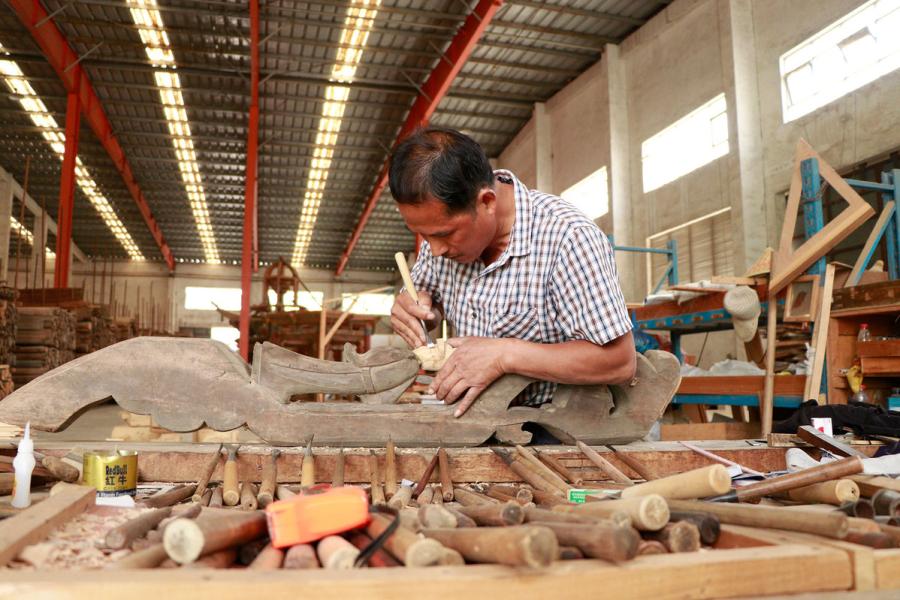 A craftsman repairs a wooden component from an ancient residence in the warehouse of Bengbu Ancient Residence Exhibition Park based in Bengbu, East China\'s Anhui province, on May 28, 2019. （By Zhu Lixin/chinadaily.com.cn）