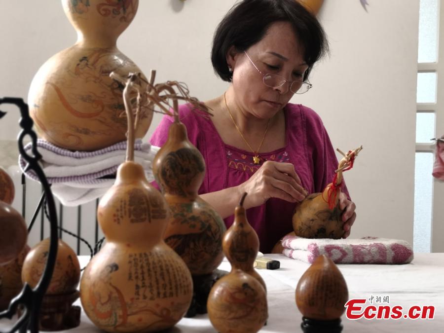 Craftswoman Chen Bing puts the final touch to a gourd in Lanzhou City, Gansu Province in June 2019.  The second generation in her family to make artistic creations on gourds, she carved  characters sometimes just one millimeter in size. (Photo: China News Service/Yang Na)