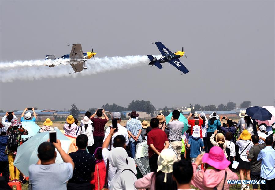 People watch an aerobatic show by enthusiasts in air sports during the opening of the 11th Air Sports Culture and Tourism Festival in Anyang, central China\'s Henan Province, June 3, 2019. The event kicked off Monday in the city of Anyang, attracting air sports fans from home and abroad. (Xinhua/Li An)
