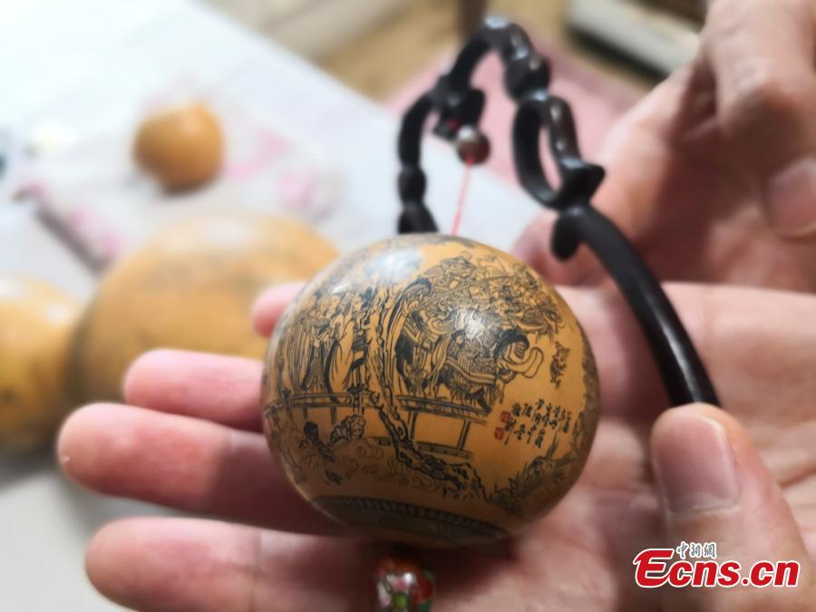 Craftswoman Chen Bing shows a gourd she carved in Lanzhou City, Gansu Province in June 2019.  The second generation in her family to make artistic creations on gourds, she carved  characters sometimes just one millimeter in size. (Photo: China News Service/Yang Na)