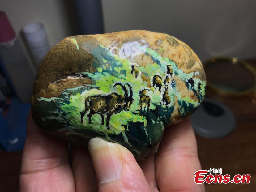 Zhang Yulin shows a paintings on a stone.Zhang, 81, from southwest China’s Chongqing municipality, collects stones from the Yangtze River banks and turns them into artworks with paintings.  (Photo: China News Service/Xiao Jiangchuan)
