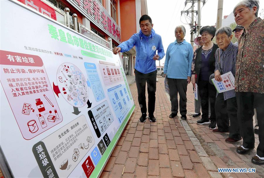 A volunteer illustrates the knowledge of garbage sorting to the local residents in Qinhuangdao, north China\'s Hebei Province, June 4, 2019. Various activities are held across the country to raise people\'s awareness of garbage sorting and help them develop the habit of waste classification. (Xinhua/Cao Jianxiong)