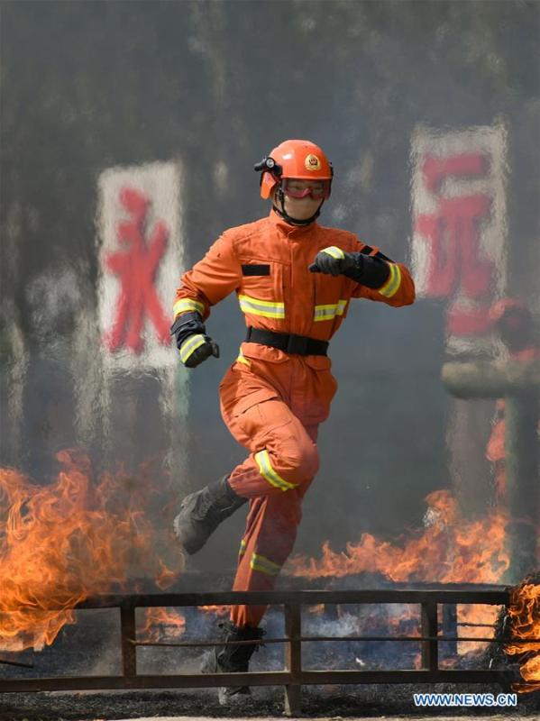 A newly-recruited fireman leaps over a fire barrier during a training in Hohhot, north China\'s Inner Mongolia Autonomous Region, June 5, 2019. Over 1,100 socially-recruited firemen are receiving a six-month training in Hohhot. (Xinhua/Peng Yuan)