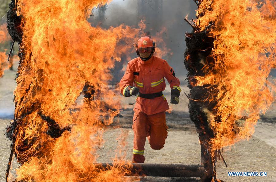 A newly-recruited fireman runs through a fire wall during a training in Hohhot, north China\'s Inner Mongolia Autonomous Region, June 5, 2019. Over 1,100 socially-recruited firemen are receiving a six-month training in Hohhot. (Xinhua/Peng Yuan)