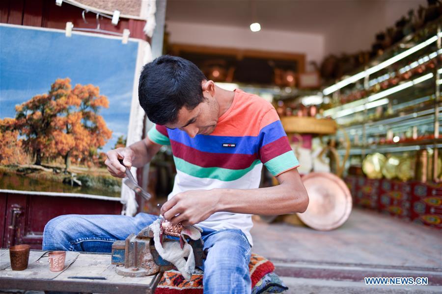 A craftsman works on a bronze ware in the ancient city of Kashgar, northwest China\'s Xinjiang Uygur Autonomous Region, June 12, 2019. The ancient city of Kashgar has been well prepared for the peak tourism season through multiple measures including improving infrastructure and service quality as well as staging acrobatics performances to help tourists better experience the time-honored folk culture here. (Xinhua/Zhao Ge)