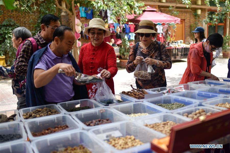 Tourists choose local specialties in the ancient city of Kashgar, northwest China\'s Xinjiang Uygur Autonomous Region, June 12, 2019. The ancient city of Kashgar has been well prepared for the peak tourism season through multiple measures including improving infrastructure and service quality as well as staging acrobatics performances to help tourists better experience the time-honored folk culture here. (Xinhua/Zhao Ge)