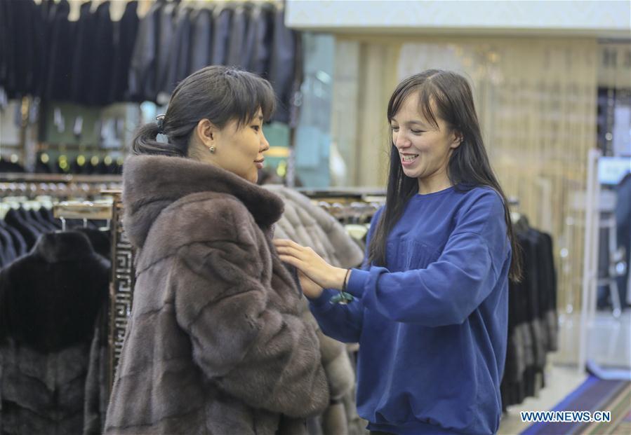 A trader from Kazakhstan helps a customer try on clothes at the China-Kazakhstan Horgos International Border Cooperation Center in Horgos, northwest China\'s Xinjiang Uygur Autonomous Region, June 12, 2019. With the Belt and Road Initiative, the trade between Xinjiang, Kyrgyzstan and Tajikistan has continued to develop. On the southern border of Xinjiang, three ports, Turugart, Erkeshtam and Karasu, between China and Kyrgyzstan and Tajikistan, saw large quantities of goods cleared by customs every year. (Xinhua/Zhou Xu)