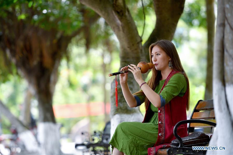 Takyrbasheva Asel, a student from Kyrgyzstan, plays the Hulusi, a free-reed wind instrument from China, at the campus of Hainan University in Haikou, south China\'s Hainan Province, June 13, 2019. Kyrgyz girl Takyrbasheva Asel majors in Tourism Management in Hainan University. She has dedicated herself in experiencing the Chinese culture, including the learning of traditional Chinese musical instruments, Taiji and martial arts, and tea art since she came to China three years ago. She hoped she could stay in China after graducation and invite people from her hometown to come and experience the Chinese culture. Statistics showed that over 4,600 Kyrgyz students studied in China in 2018. (Xinhua/Guo Cheng)