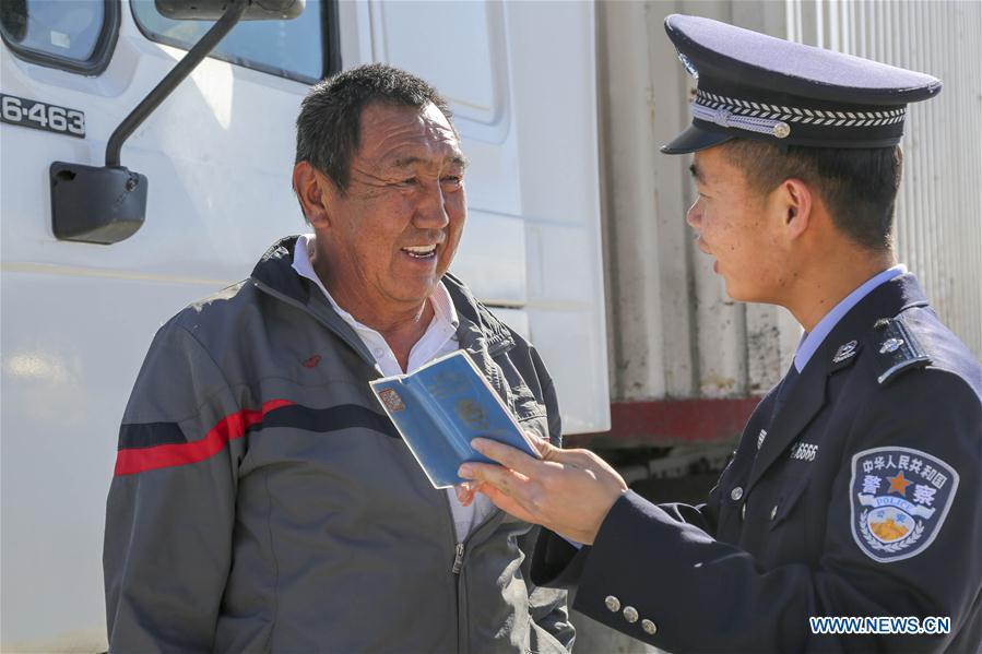 A Chinese border policeman introduces entry-exit related matters to a driver from Kyrgyzstan in Erkeshtam port, northwest China\'s Xinjiang Uygur Autonomous Region, June 11, 2019. With the Belt and Road Initiative, the trade between Xinjiang, Kyrgyzstan and Tajikistan has continued to develop. On the southern border of Xinjiang, three ports, Turugart, Erkeshtam and Karasu, between China and Kyrgyzstan and Tajikistan, saw large quantities of goods cleared by customs every year. (Xinhua/Luo Yang)