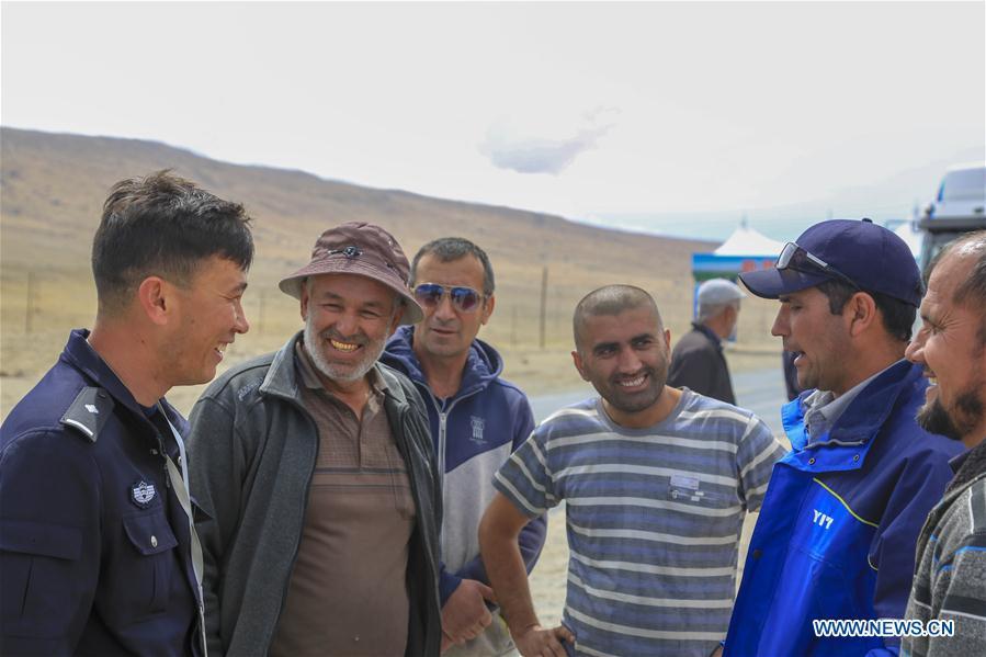 A Chinese border policeman (1st L) introduces entry-exit related matters to drivers from Tajikistan in Karasu port, northwest China\'s Xinjiang Uygur Autonomous Region, June 11, 2019. With the Belt and Road Initiative, the trade between Xinjiang, Kyrgyzstan and Tajikistan has continued to develop. On the southern border of Xinjiang, three ports, Turugart, Erkeshtam and Karasu, between China and Kyrgyzstan and Tajikistan, saw large quantities of goods cleared by customs every year. (Xinhua/Huang Huan)