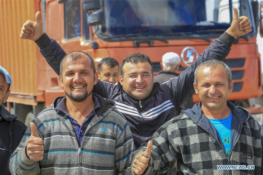 Passengers from Tajikistan pose for a group photo in Karasu port, northwest China\'s Xinjiang Uygur Autonomous Region, June 11, 2019. With the Belt and Road Initiative, the trade between Xinjiang, Kyrgyzstan and Tajikistan has continued to develop. On the southern border of Xinjiang, three ports, Turugart, Erkeshtam and Karasu, between China and Kyrgyzstan and Tajikistan, saw large quantities of goods cleared by customs every year. (Xinhua/Huang Huan)