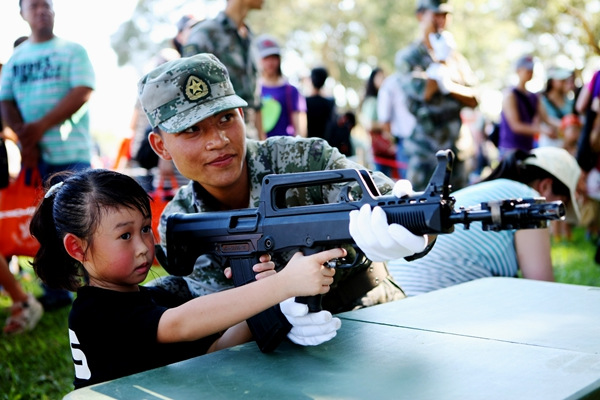 A soldier from the People's Liberation Army Hong Kong Garrison teaches a child to use a mock laser gun. ZHOU HANQING/CHINA DAILY A soldier from the People's Liberation Army Hong Kong Garrison teaches a child to use a mock laser gun. ZHOU HANQING/CHINA DAILY