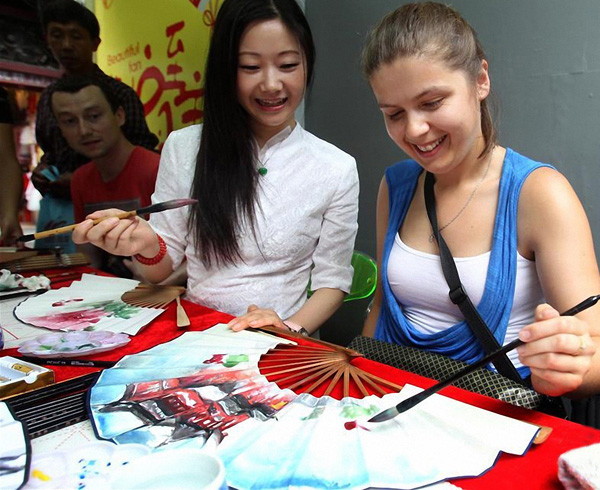 A foreign tourist learns to paint on a traditional Chinese fan in Shanghai in July. (Photo/Xinhua) A foreign tourist learns to paint on a traditional Chinese fan in Shanghai in July. (Photo/Xinhua)