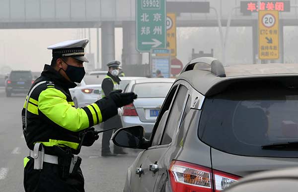 A traffic officer directs a driver at a toll station in Shijiazhuang, Hebei province, on Monday after the freeway linking Beijing and Hong Kong was partially closed due to heavy smog. ZHAI YUJIA/CHINANEWS SERVICE A traffic officer directs a driver at a toll station in Shijiazhuang, Hebei province, on Monday after the freeway linking Beijing and Hong Kong was partially closed due to heavy smog. ZHAI YUJIA/CHINANEWS SERVICE