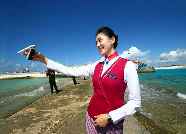 A stewardess takes a selfie after a Chinese aircraft lands on the newly constructed runway at Yongshu Jiao in China's Nansha Islands during a test flight on Jan 6. (Photo/Xinhua) A stewardess takes a selfie after a Chinese aircraft lands on the newly constructed runway at Yongshu Jiao in China's Nansha Islands during a test flight on Jan 6. (Photo/Xinhua)