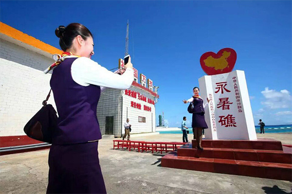 A stewardess takes a photo standing beside a monument with Chinese characters of Yongshu Jiao inscribed on it. (Photo/Xinhua) A stewardess takes a photo standing beside a monument with Chinese characters of Yongshu Jiao inscribed on it. (Photo/Xinhua)