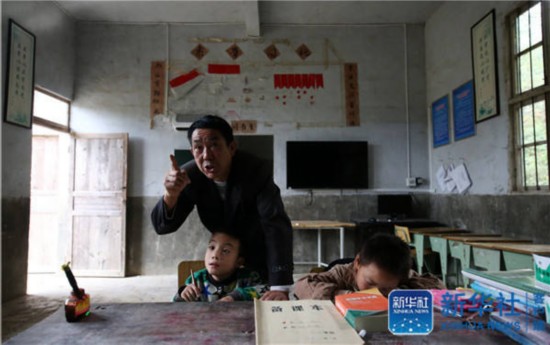 Yang Jinhua, the only teacher in Muqiao primary school, helps students with their homework on October 24, 2016. (Photo/Xinhua)