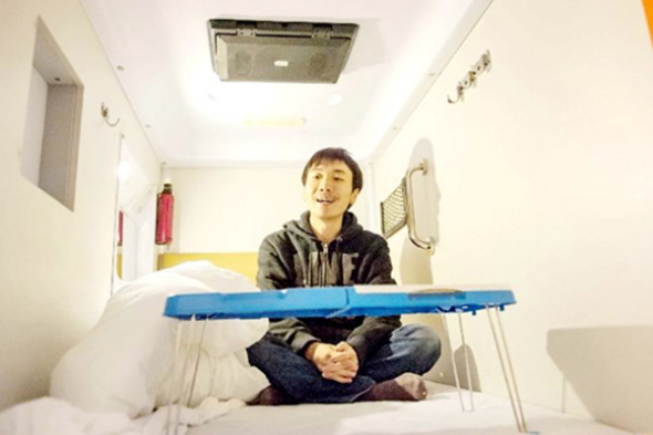 A guest erected a collapsible desk in a capsule hotel in Chongqing in 2012. (Photo/Xinhua)